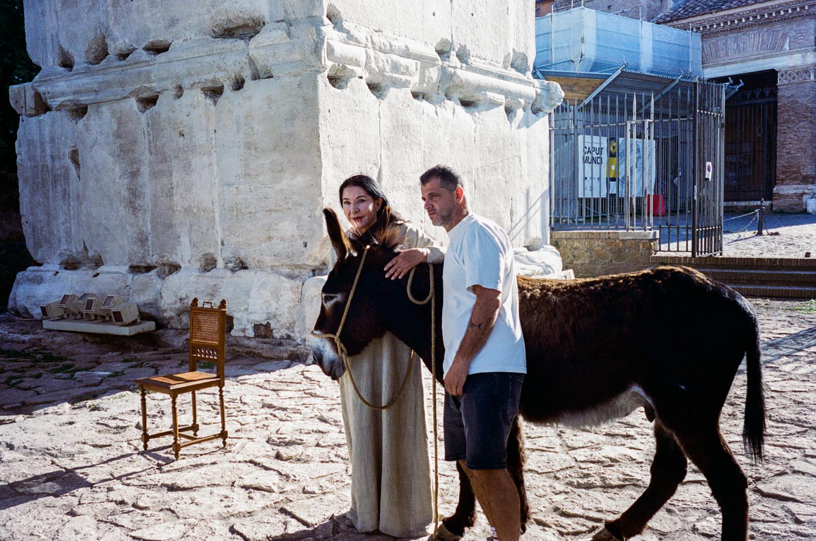 The model standing by a column with a crew member holding the donkey's lead